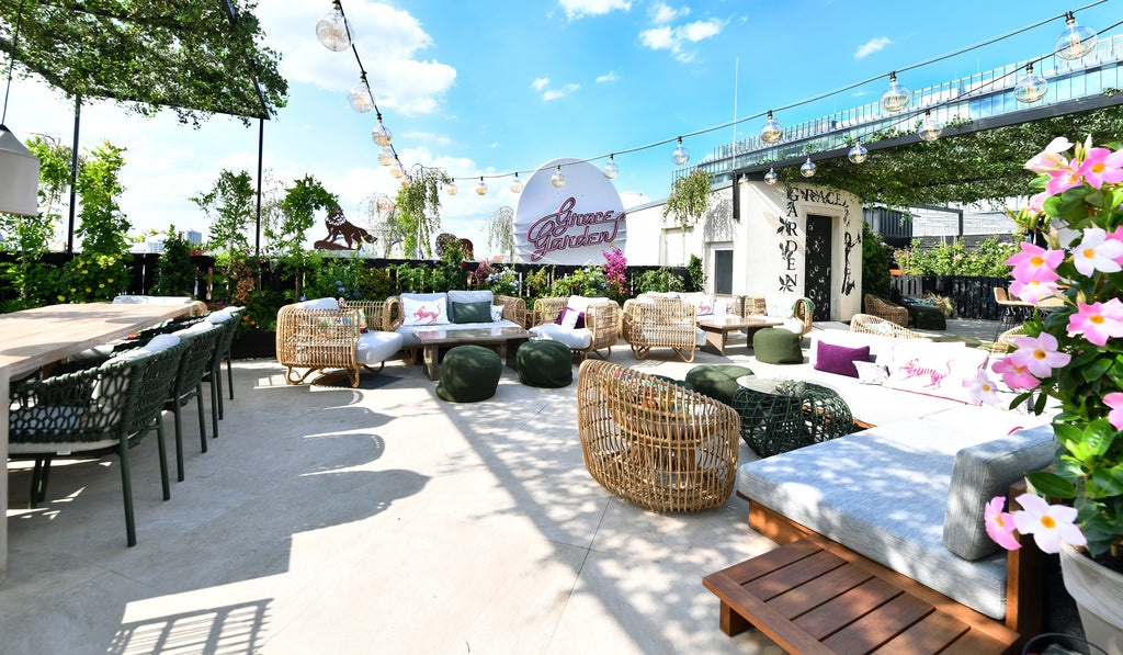 Roofttop bar and lounge terrace at Grace Garden, Berlin. Large outdoor terrace, Cane-line Ocean dining chairs with dark green soft rope, Round chair and lounge chairs from Cane-line Nest collection in nature, pink flowers, green plants