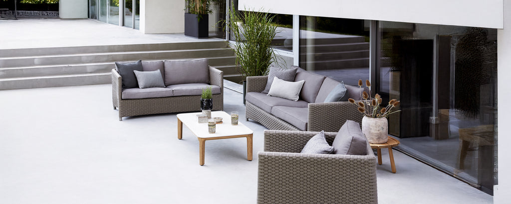 Modern outdoor lounge setup with grey sofa, armchair, and white table.