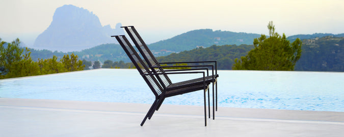 Modern black chair positioned near a pool with a scenic background.