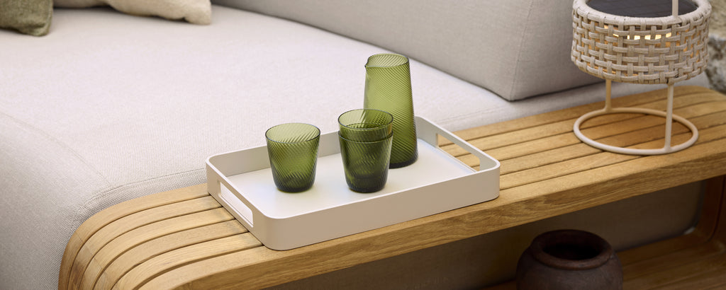 Modern lounge setting featuring green glassware on a white tray.