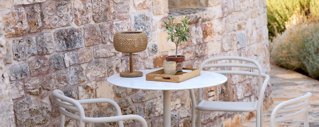 Modern outdoor setting with white table, white chairs, and brown decor elements.
