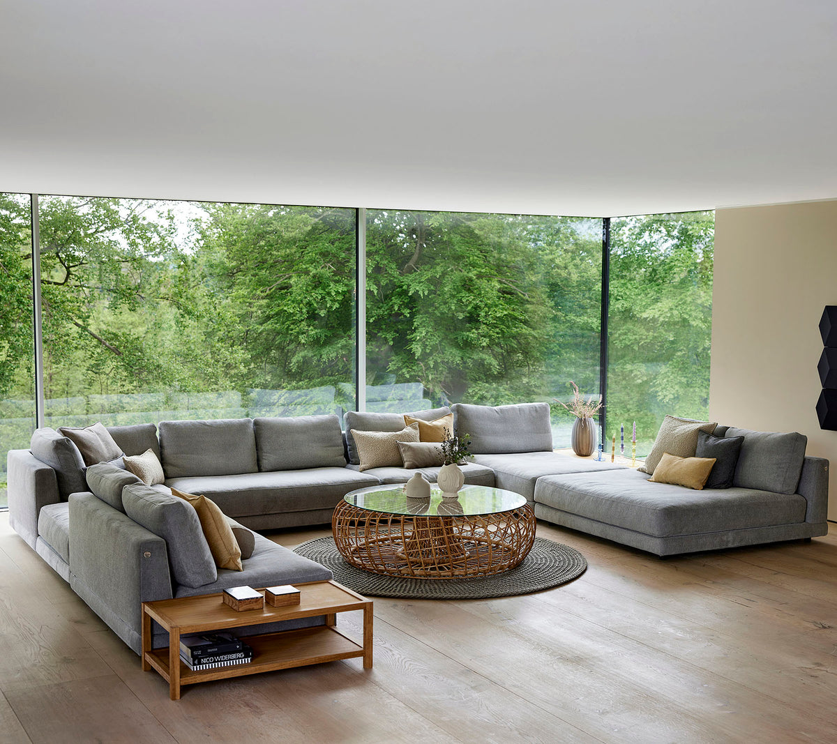 Spacious living area featuring a large sectional sofa, coffee table, and decorative accents, surrounded by natural light and greenery.