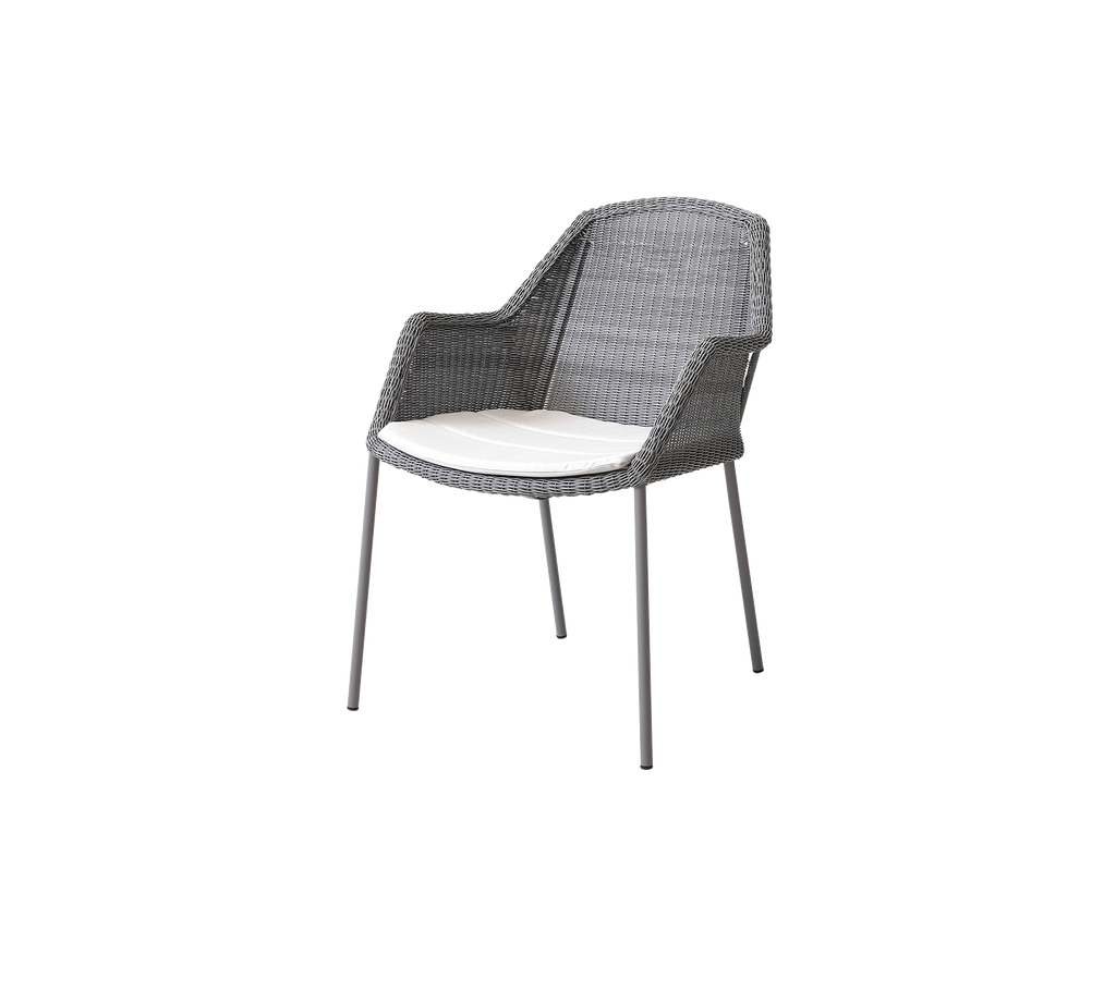 Gray woven chair with a comfortable white cushion, featuring armrests and sleek metallic legs, ideal for modern seating arrangements.