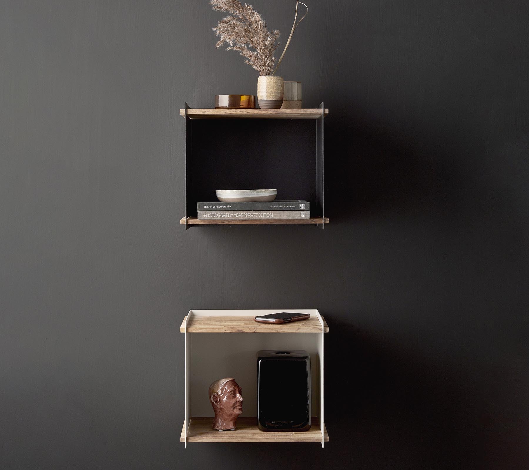 Stylish wall shelves displaying decorative items, including a vase with dried flowers, a bowl, and a small sculpture, against a dark background.