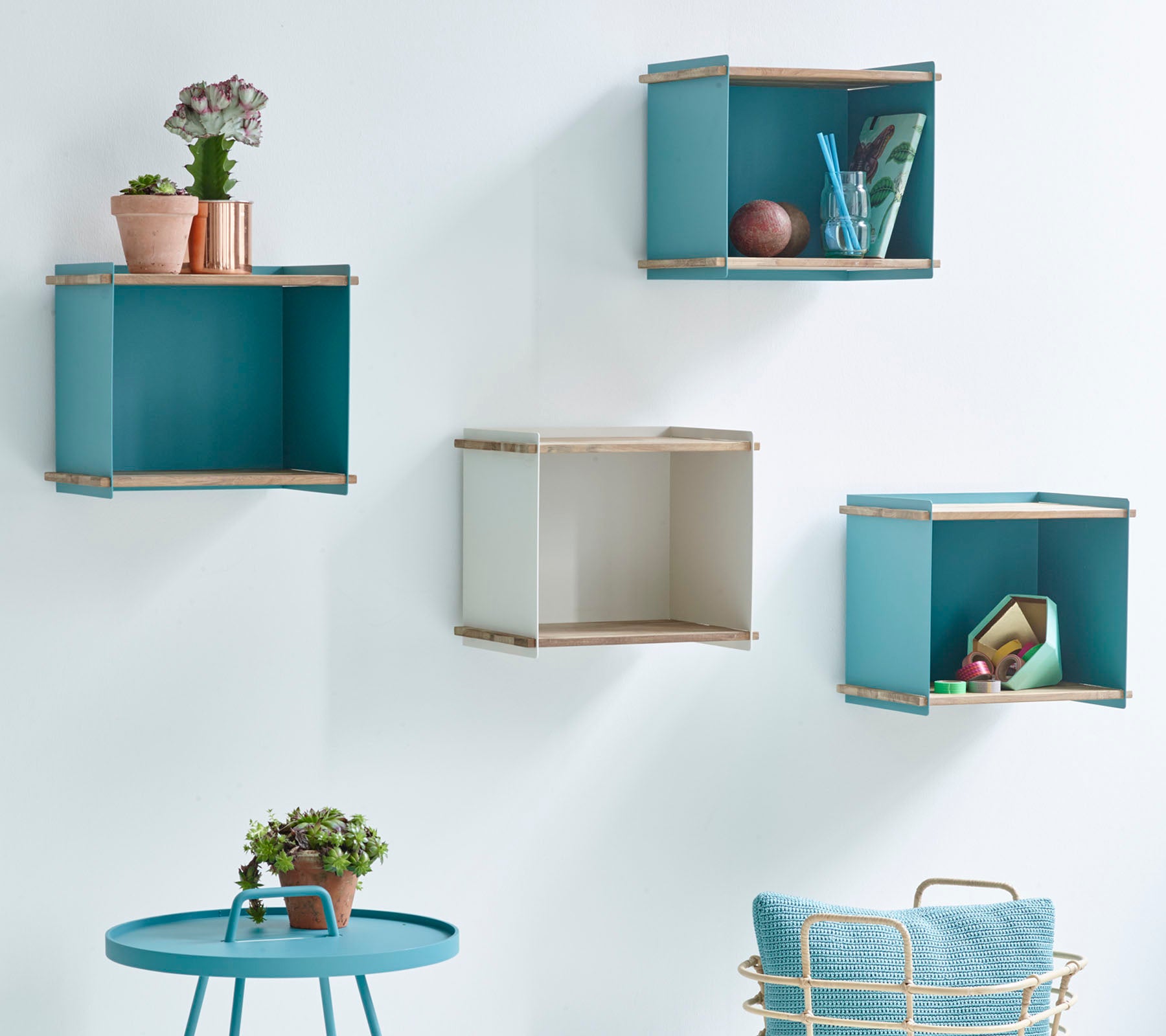 Four decorative wall-mounted storage boxes in blue and beige, accompanied by a small round table with a potted plant.