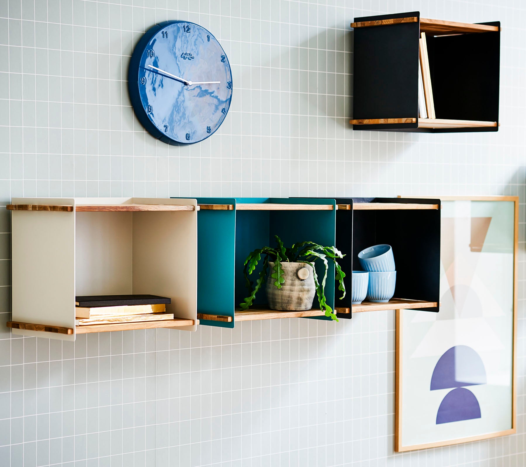 A stylish wall display featuring colorful storage boxes, a round wall clock, and framed art for a modern aesthetic.