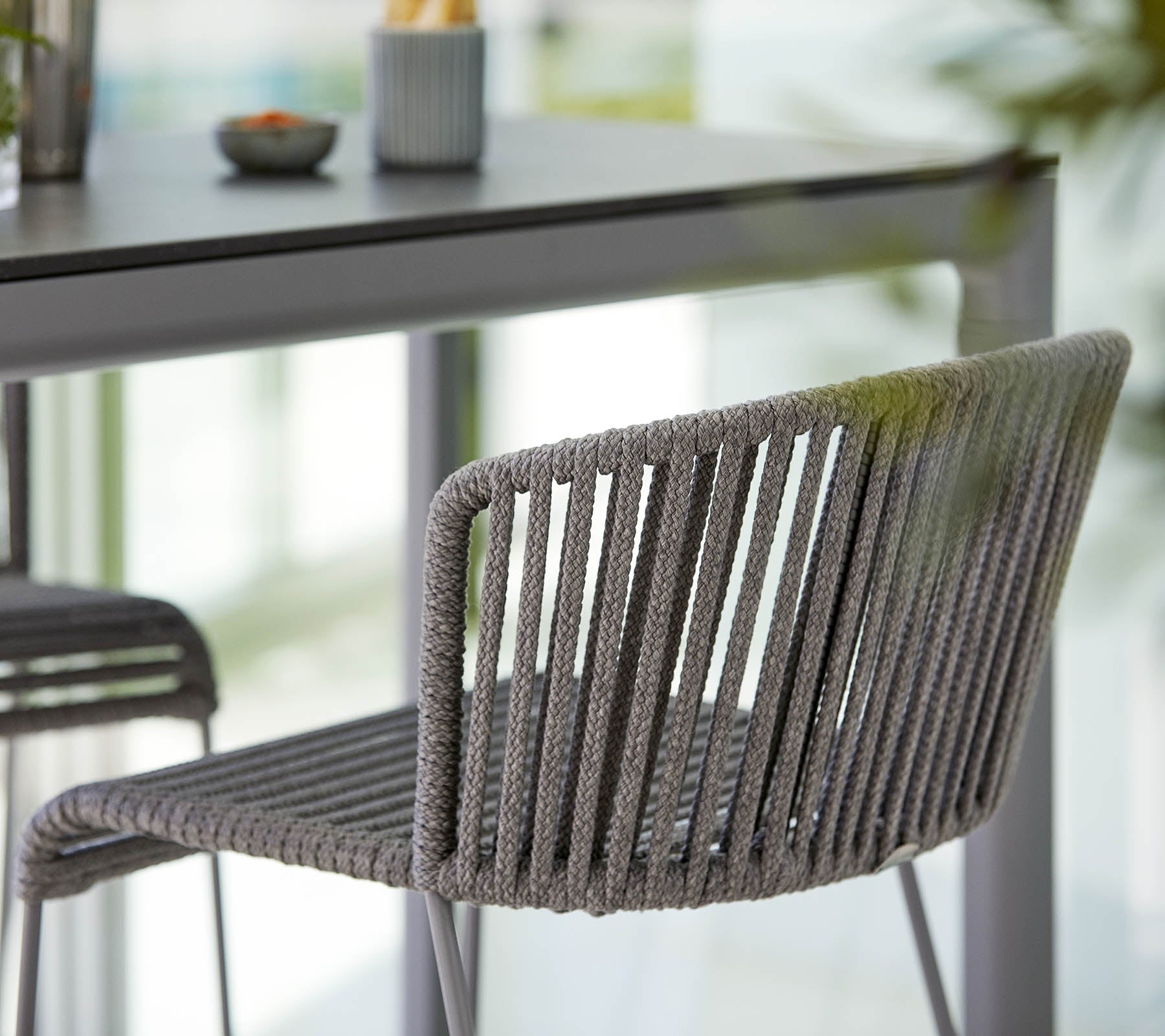 Stylish gray chair with a sleek design, featuring vertical stripes and a modern aesthetic, placed next to a minimalistic table.