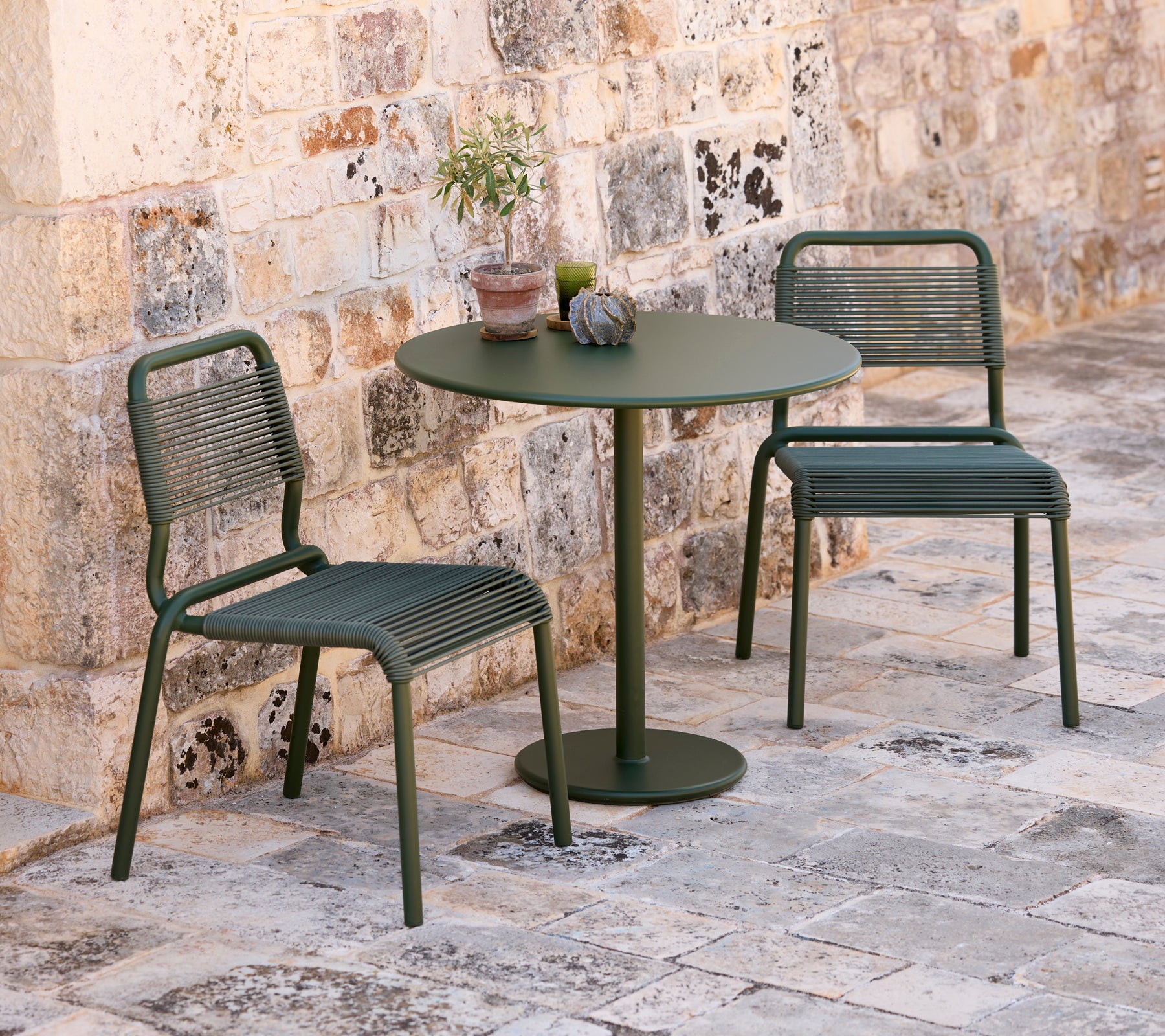 Two green chairs and a round green table in an outdoor setting.