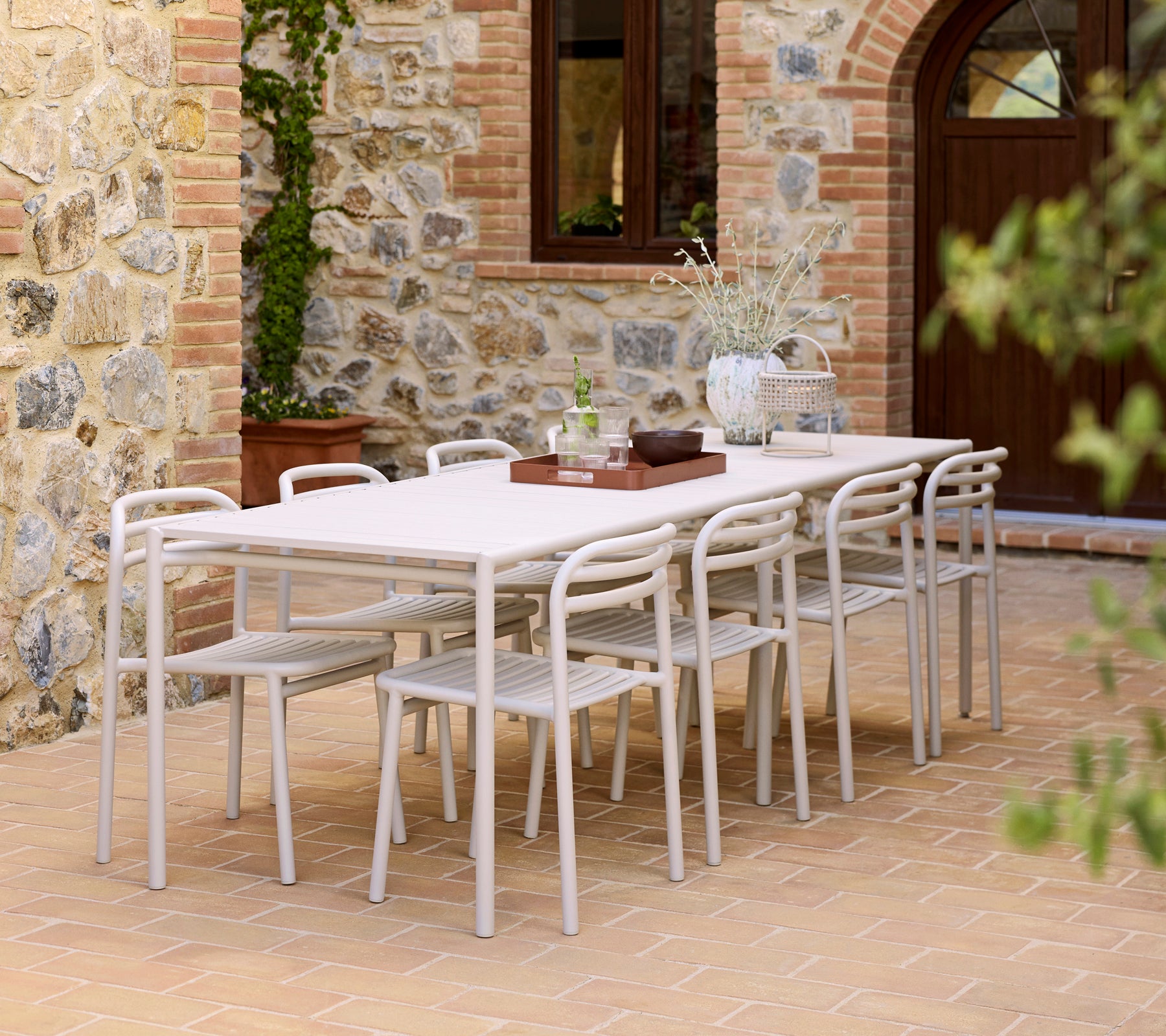 A modern dining setup featuring a Bliss table, Bliss chairs, and a Club tray on a textured surface.