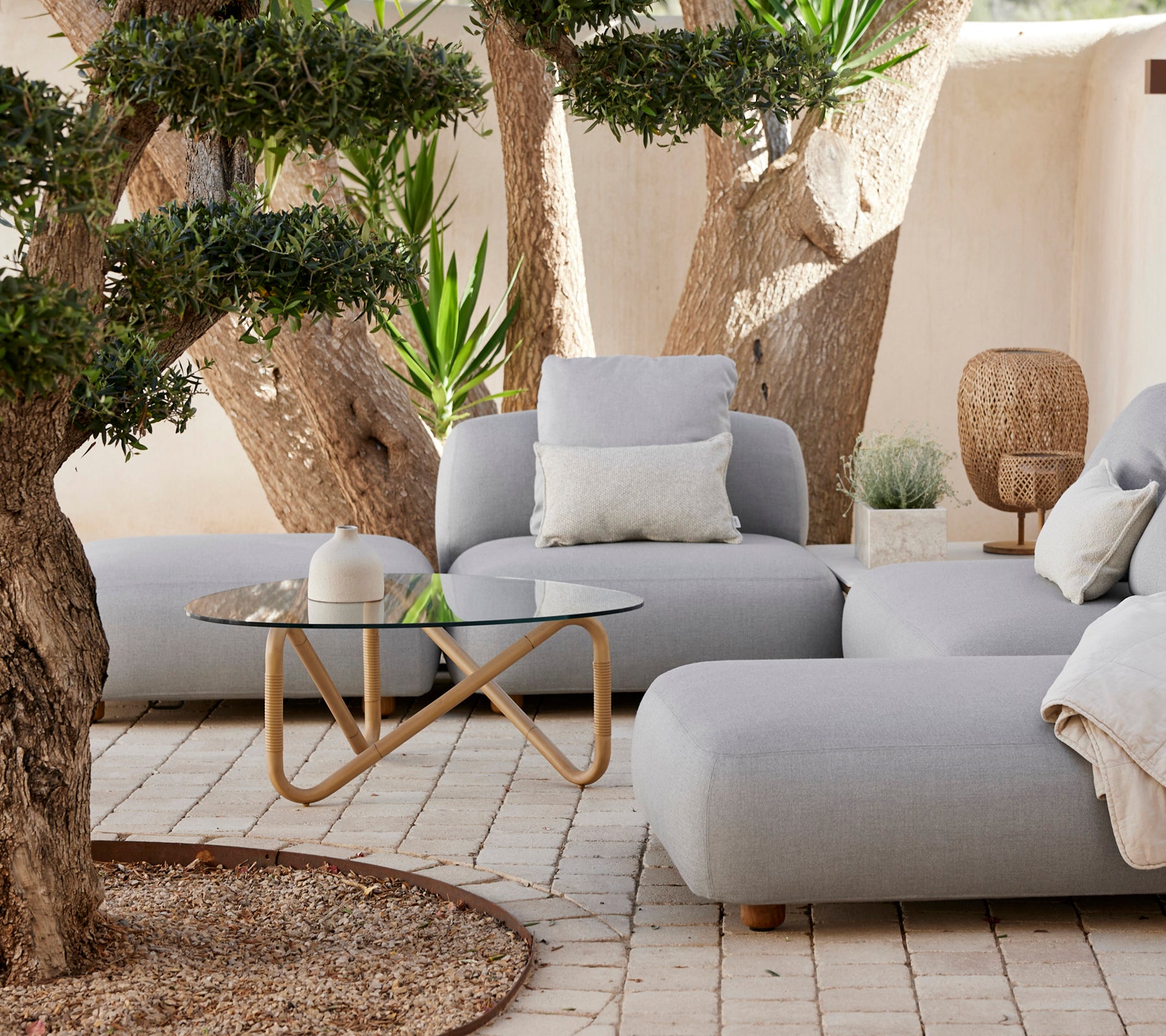 Modern lounge area featuring a grey sofa, white pillow, and glass coffee table.