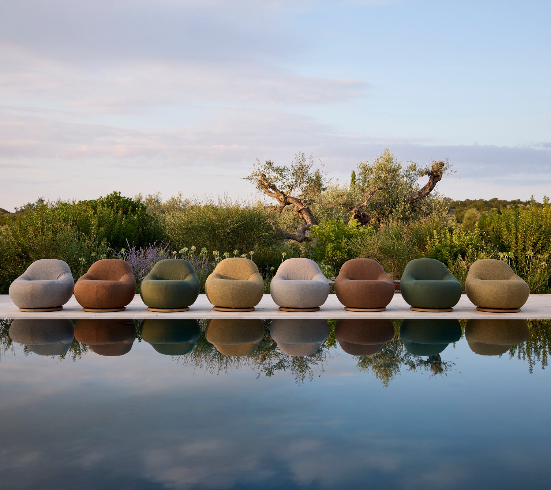 Contemporary outdoor chairs in various colors arranged by a poolside.