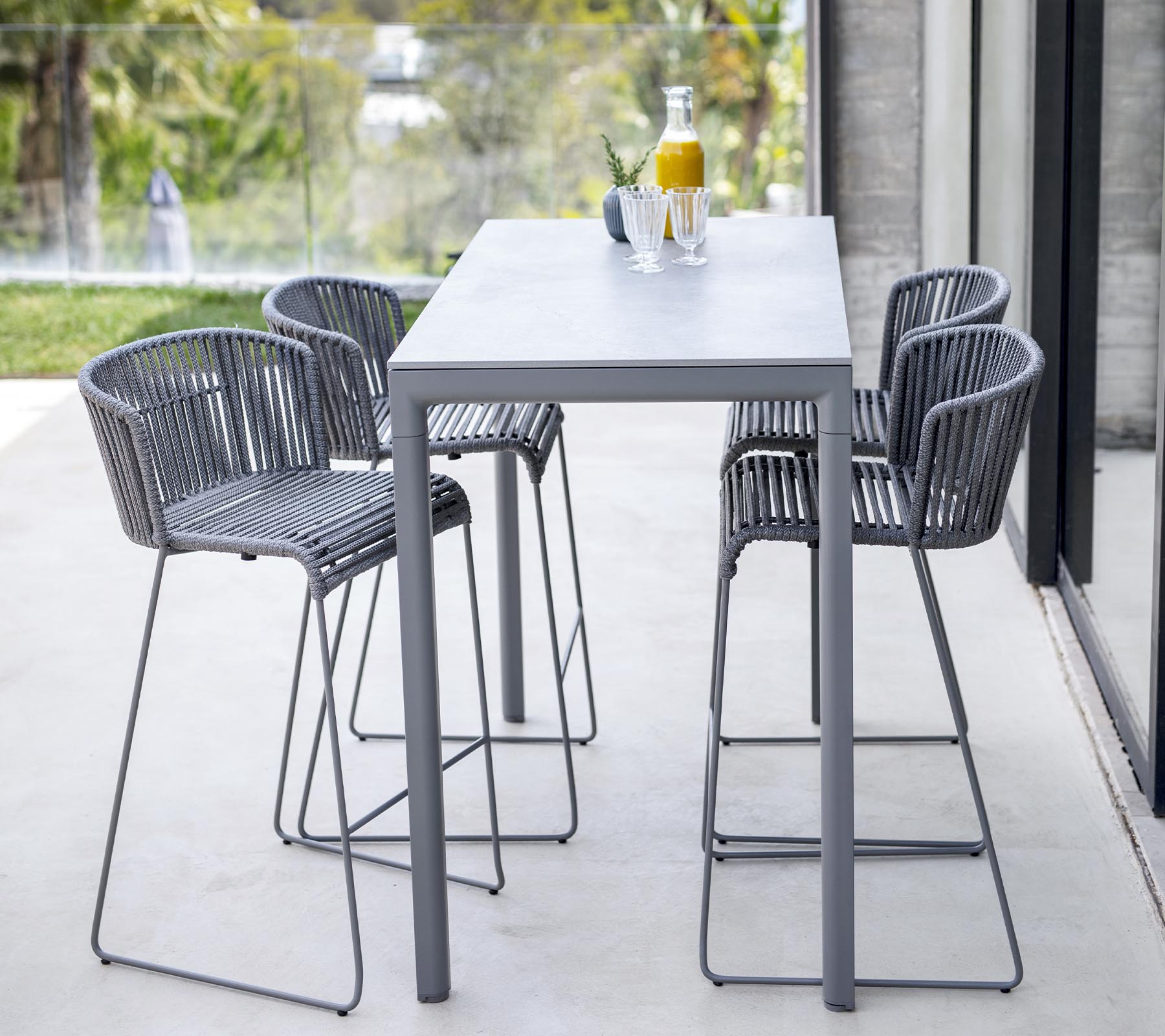 Modern dining set featuring a sleek table and four high-backed chairs with a minimalist design, ideal for casual gatherings.