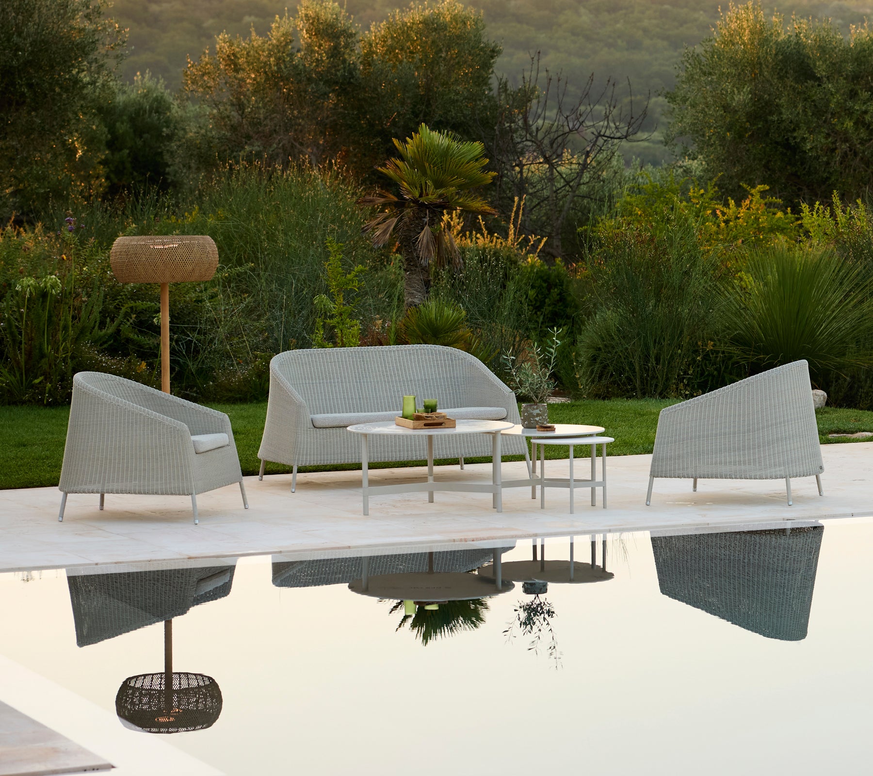 Modern grey sofa and chair with white table in an outdoor lounge setting.
