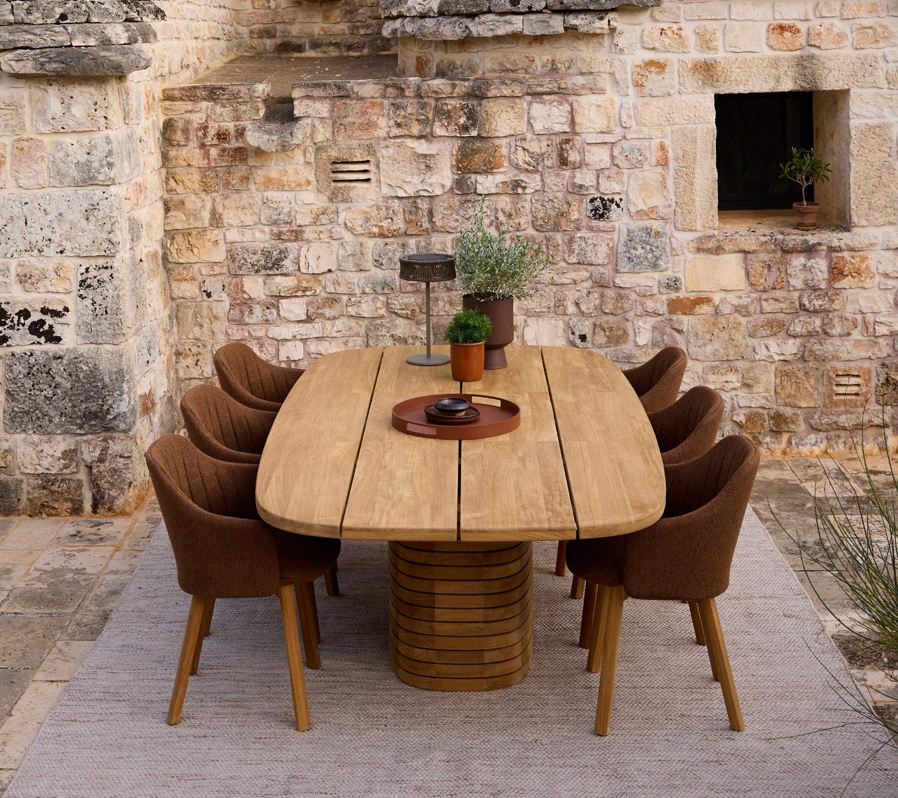 Modern wooden dining table surrounded by brown chairs in a rustic setting.