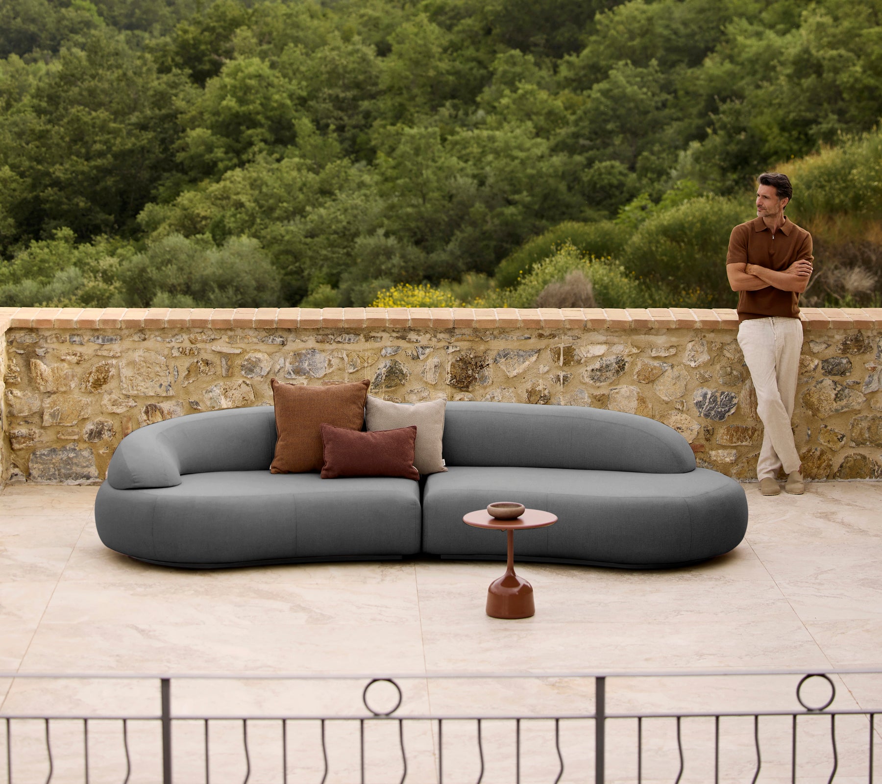 Mellow lounge sofa with cushions beside a sleek Glaze coffee table, set against a natural backdrop.