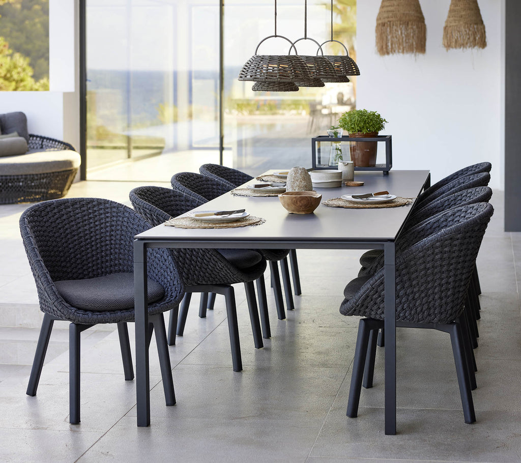 A stylish dining setup featuring a pure dining table, peacock chairs, and an illusion lamp, enhancing a modern aesthetic.