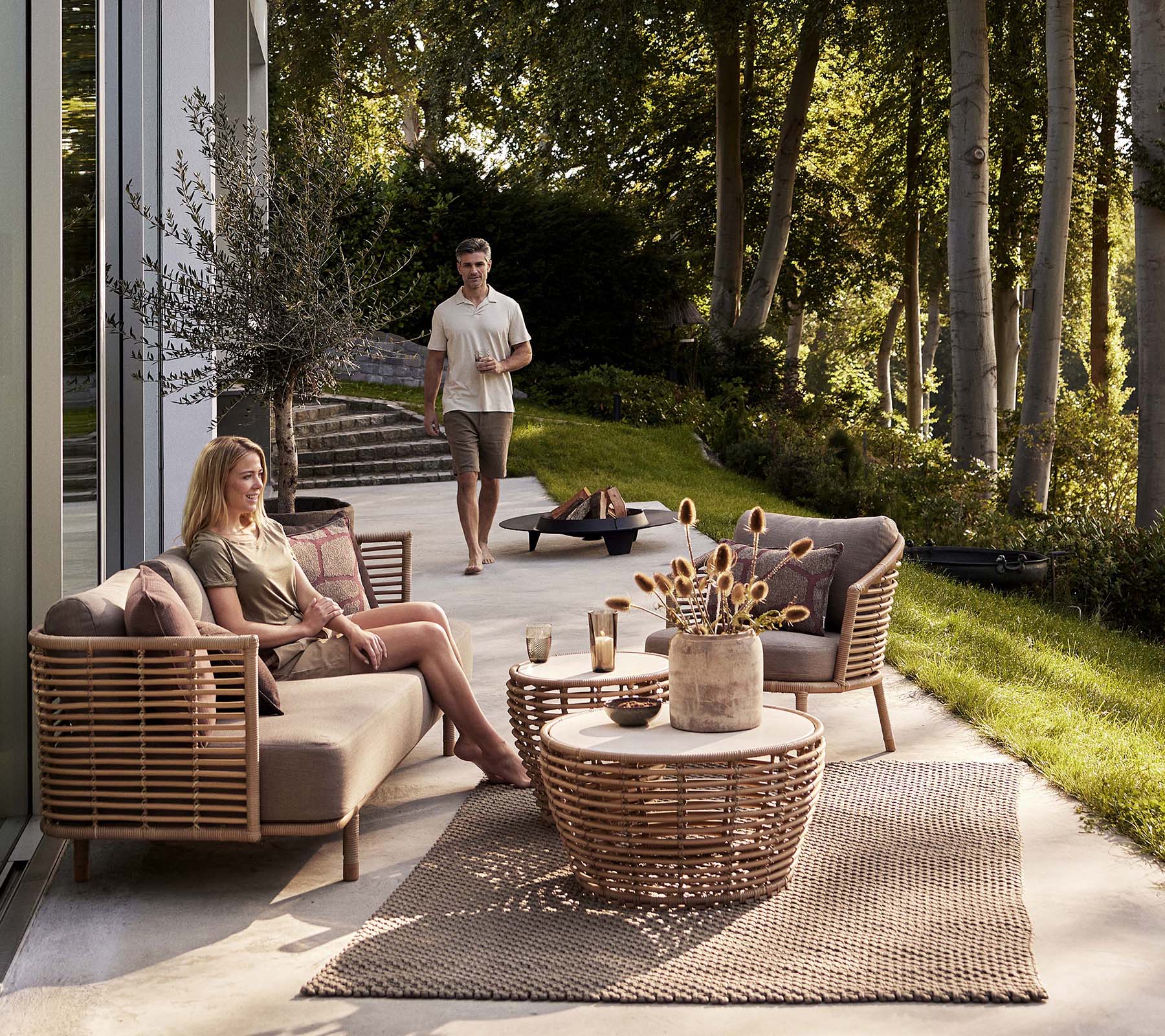 A cozy seating arrangement featuring a Sense sofa and lounge chair, accompanied by a basket coffee table and decorative elements.