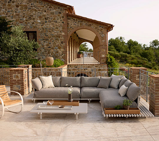 Cozy seating arrangement featuring a grey sofa and a modern coffee table with a planter, set against a scenic backdrop.