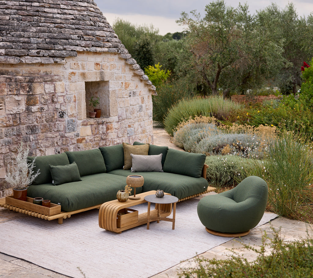 Modern green sofa with round chair and coffee table in an outdoor lounge setting.
