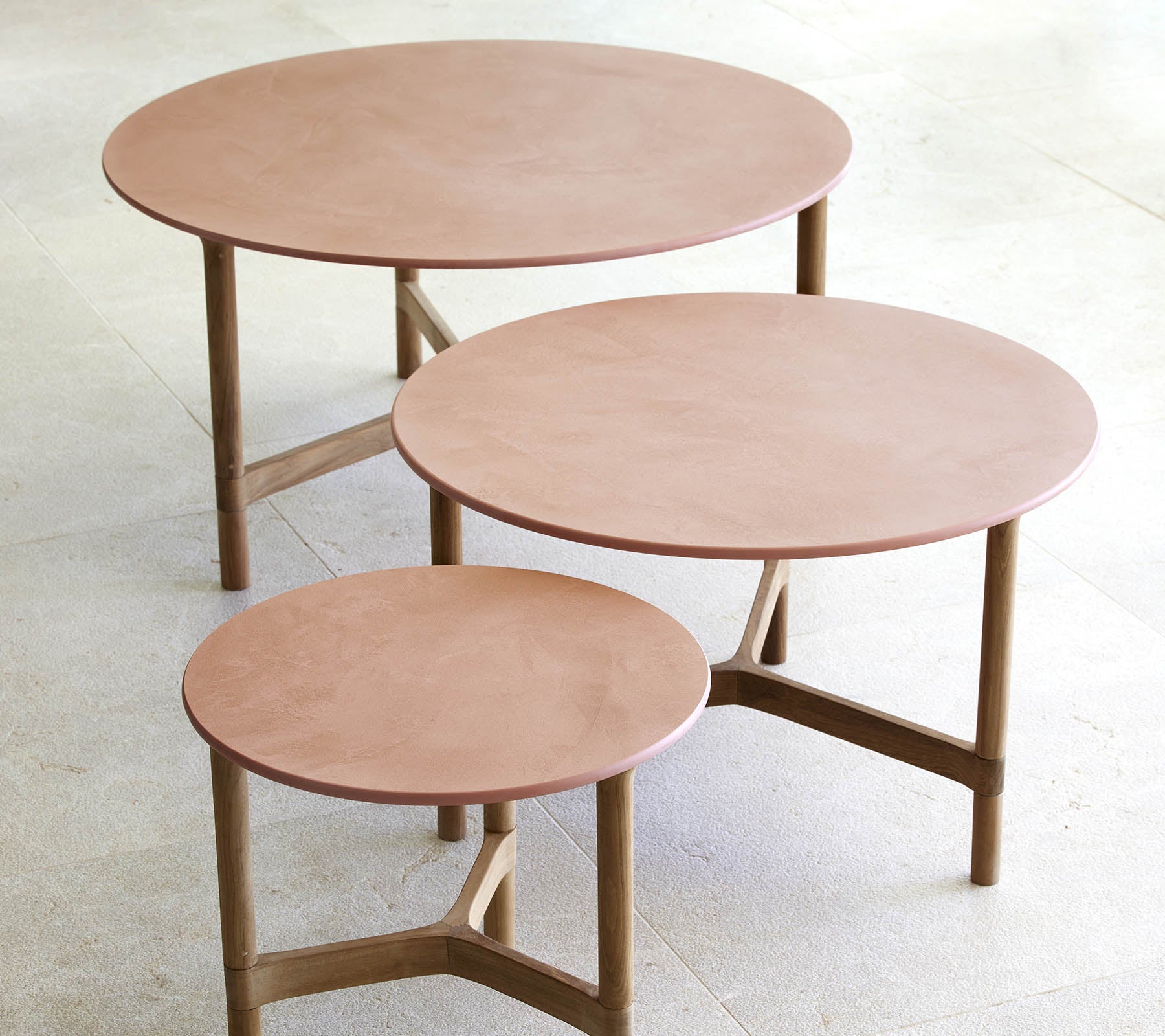 Three circular coffee tables in varying sizes, featuring a minimalist design with wooden legs and a smooth, elegant surface.