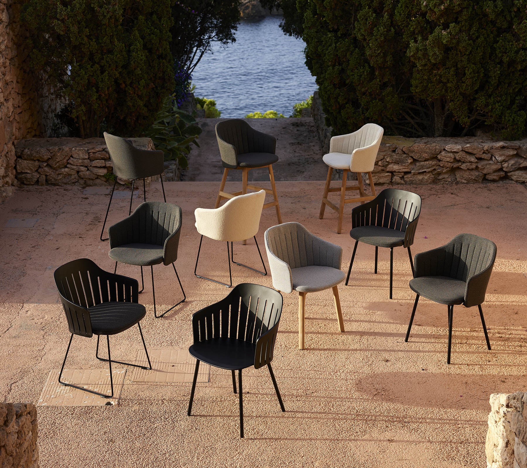 A collection of stylish chairs in various colors arranged in a scenic setting, showcasing versatile design choices.